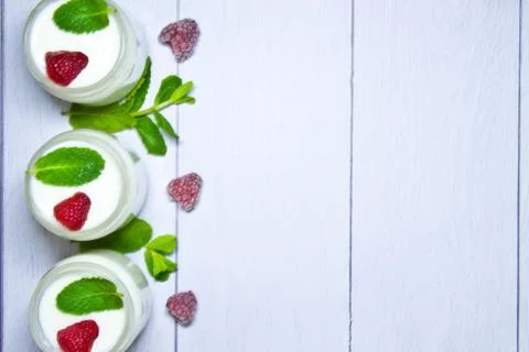 Fresh composition with yogurt in cans of mint leaves and frozen raspberries Stock Photos