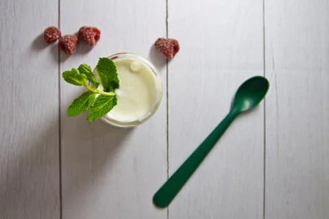 Fresh composition with yogurt in cans of mint leaves and raspberries next to Stock Photos