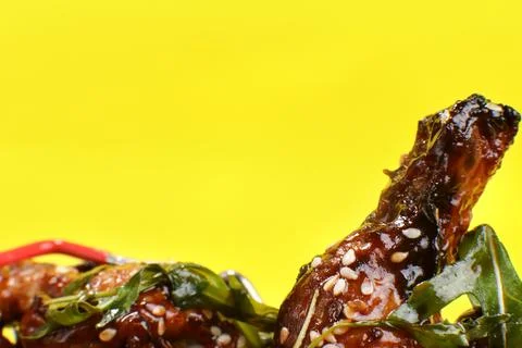 Fresh cooked delicious chicken wings in a plastic container isolated on a yellow Stock Photos