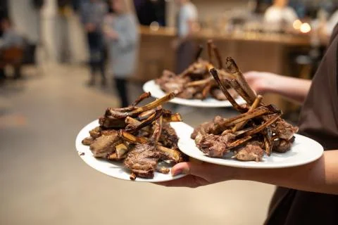 Fresh cooked lamb chops on plate being served by waiter Stock Photos
