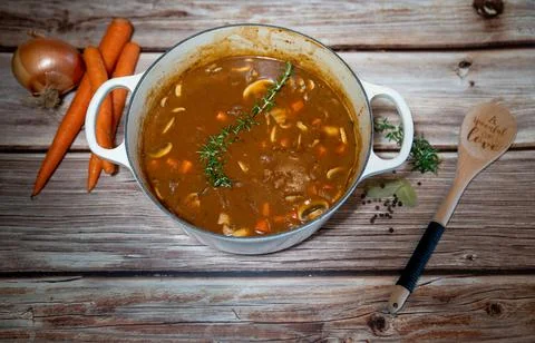 Fresh cooked stew in a rustic pot on a wooden background, spoonful of love 写真素材