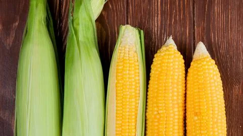 Fresh corn on the cob with husks and kernels visible Stock Photos
