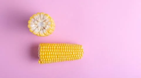 Fresh corn on a colored background. Scattered grains, halves of the product. Stock Photos