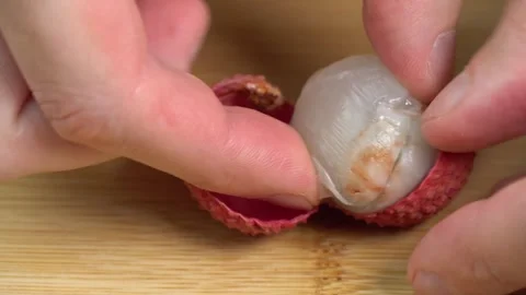 Fresh cracked lychee fruit in shell rotate in macro on wooden background. Lychee Stock-Footage 244811306