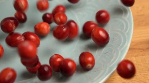 Fresh cranberries fall onto blue plate, slow motion Video stock 84057973