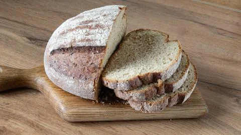 Fresh, crisp sourdough bread on the table. Slicing French whole grain bread f Stock Photos