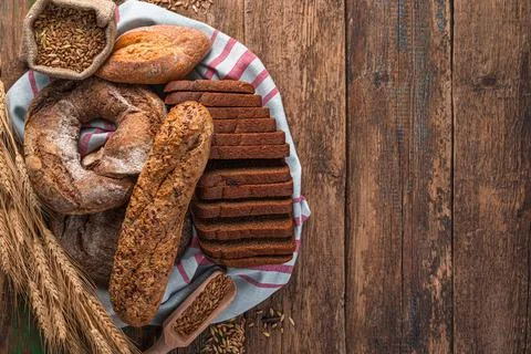 Fresh, crispy bread of various kinds on a wooden table. Stock Photos