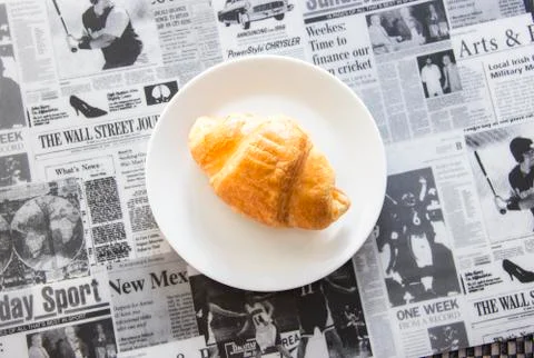 Fresh croissant on newspaper pattern Stock Photos