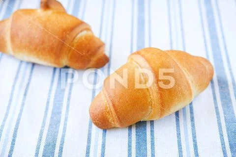 Fresh croissants on a striped linen towel. Freshly baked bakery products clos Stock Photos