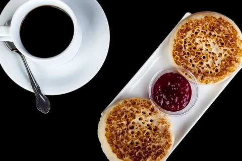 Fresh crumpets on a rectangular serving plate with black coffee Foto stock