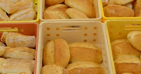 Fresh crusty bread rolls and loaves packed in perforated bakery crates, with Видео 344582797