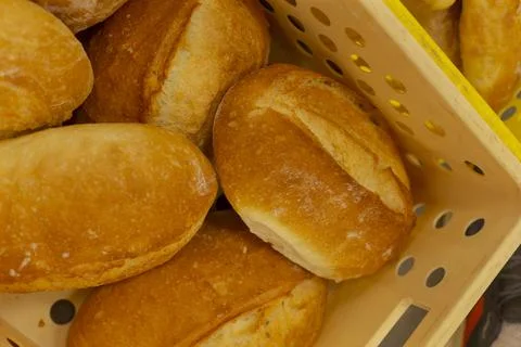 Fresh crusty bread rolls stacked in perforated plastic bakery crate close up Stockfoto's