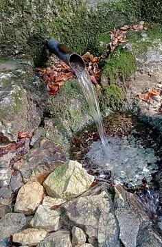 Fresh crystal clear mountain spring water flowing from a pipe Foto stock