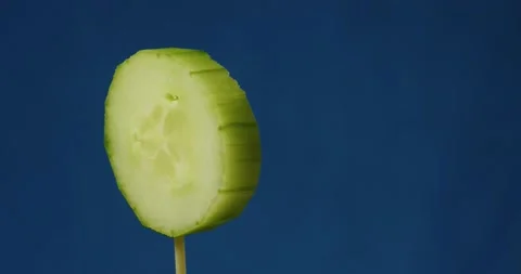 Fresh cucumber slice rotates in front of blue screen. Stock Footage 170773319