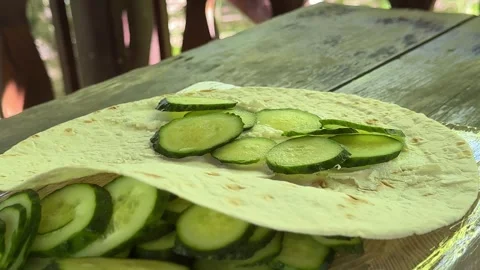 Fresh cucumber slices placed on lavash with soft cream cheese on wooden table Stock Footage 345721528