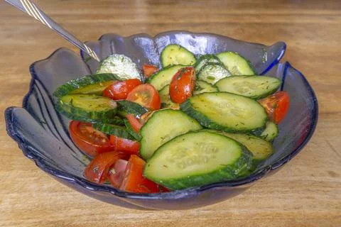 Fresh cucumbers and cherry tomatoes in a blue bowl Stock-Fotos