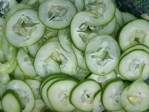 Fresh cucumbers are thinly sliced to prepare them for cooking. Stock Photos