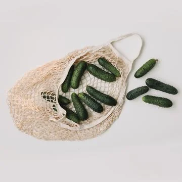 Fresh cucumbers in a reusable string bag isolated on white background top view Stock Photos