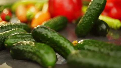 Fresh cucumbers roll into the frame on the table, creating splashes of water. Stock Footage 296362472