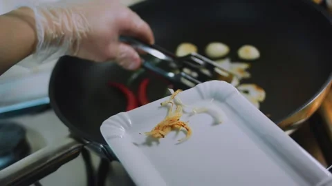 Fresh culinary close-up: spooning cooked aromatics onto a white dish Stock Footage 342179584