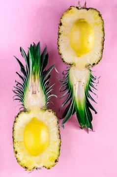 Fresh cut pineapple with upside down lemons on pink background Stock Photos