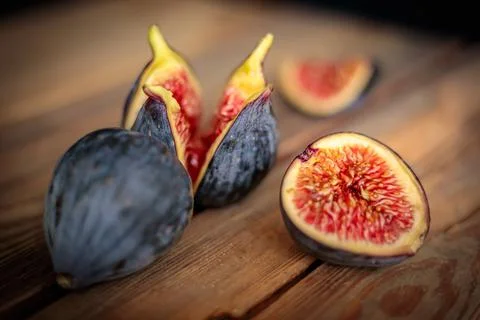 Fresh cut purple figs on a wooden background from old boards. Raw exotic figs. Stock Photos