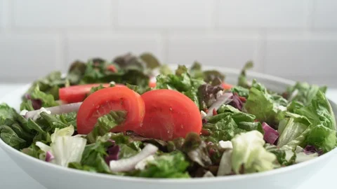 Fresh cut tomatoes falling on salad. Slow Motion. Stock Footage 121484708
