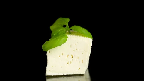 Fresh dairy cheese with aromatic basil leaves on elegant black background Stock Footage 340416109