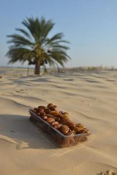 Fresh Dates in Box on Desert Sand with Palm Tree Background Foto stock