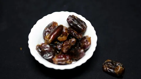 Fresh dates dropping in ceramic bowl with black background studio shot Stock Footage 296614919