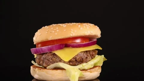 Fresh delicious cheeseburger rotating on black background with juicy beef t.. Stock Footage 332709618