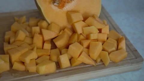 Fresh diced orange pumpkin cubes on a wooden board Stock Footage 338120941