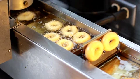 Fresh donuts gently roll down a conveyor belt in a donut shop Stock Footage 164793922