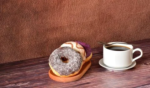 Fresh donuts in multi-colored glaze and a cup of black coffee on a dark woo.. Stock Photos