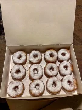 Fresh donuts with powdered sugar inside a white cardboard delivery box Stock Photos