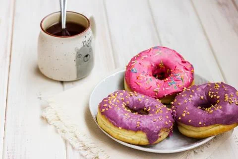 Fresh donuts in the white plate and cup of tea on wooden background Stock Photos
