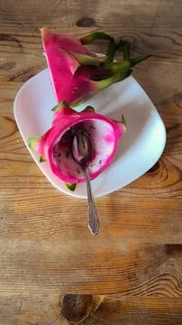 Fresh dragon fruit cut in half with spoon on white plate. Stock-Fotos