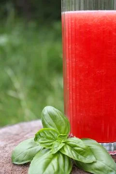 Fresh drink with basil leaf placed beside red beverage in an outdoor setting Stock Photos