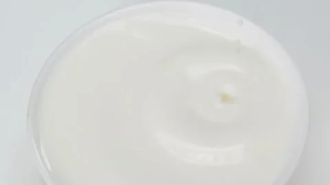 Fresh droplets of milk drop falling and splashing onto a serene pool from above Stock Footage 331378992