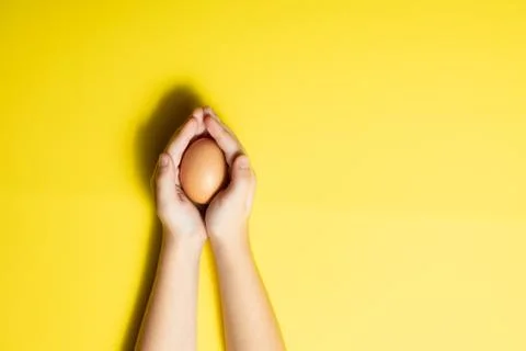Fresh Easter egg in hands on a yellow background. happy Easter Stock Photos