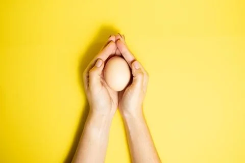 Fresh Easter egg in hands on a yellow background. happy Easter Stock Photos