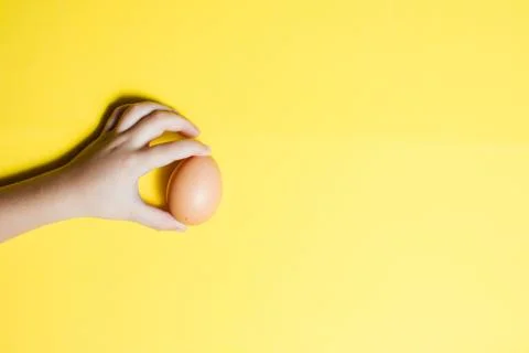Fresh Easter egg in hands on a yellow background. happy Easter Stock Photos