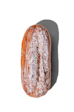 Fresh eclair with powdered sugar isolated on a white background, hard shadows Stock Photos