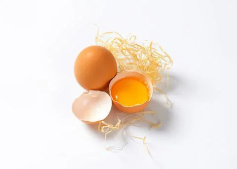 Fresh egg with broken shell showing yolk Fotos de archivo