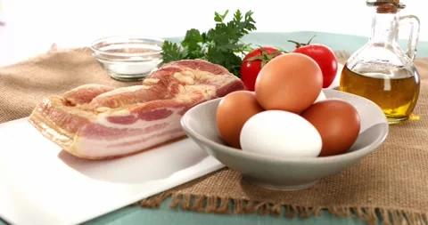 Fresh eggs, bacon, vegetables and oil. ingredients for making scrambled eggs. Stock Footage 242491965