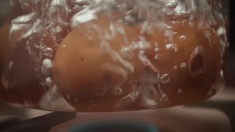 Fresh eggs boiling in water during food preparation in a kitchen. Close up of Видео 343501308