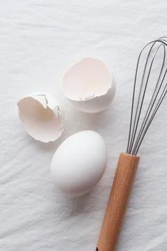 Fresh eggs, eggshells and whisk for whipping Foto stock