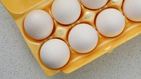Fresh eggs, packed in vibrant yellow, rest on a light surface, promoting a .. Stock Footage 260822791