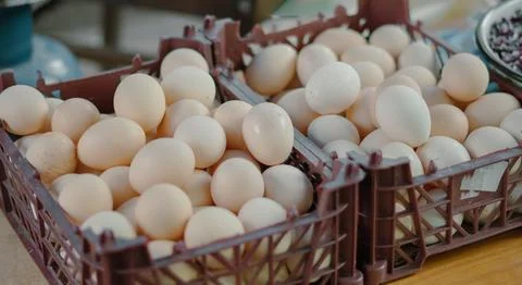 Fresh eggs in plastic crates displayed on a wooden table at market Stock Photos