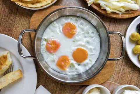 Fresh eggs in a pot served with bread and cheese at a breakfast table in a .. Stock Photos